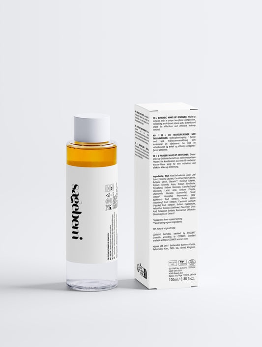 A clear bottle of makeup remover oil next to its white packaging box with text.