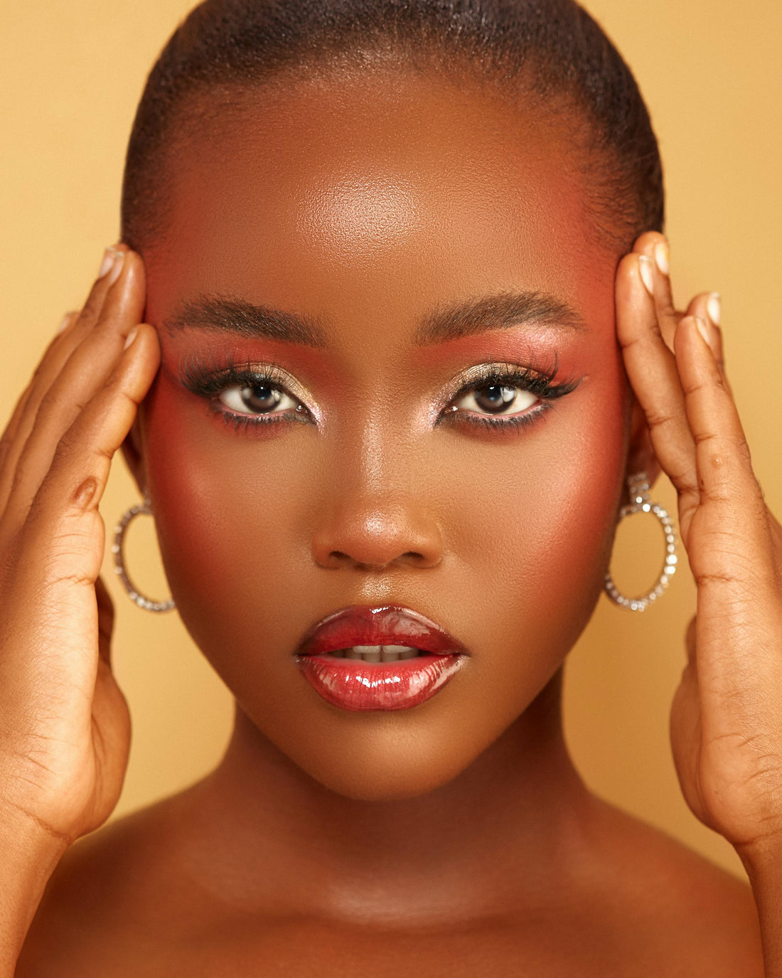 The face of a beautiful, brown-skinned young woman wearing expertly applied makeup 