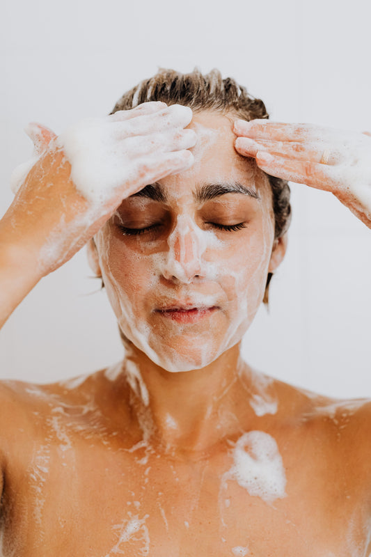 This is a picture of a young woman using a water-based cleanser on her face.