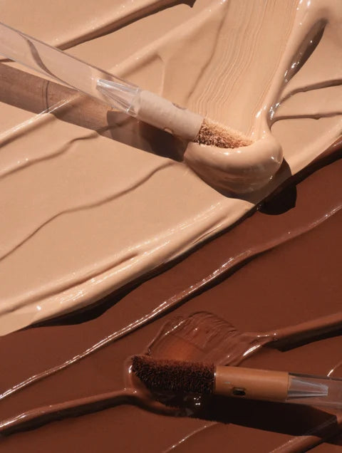 Close-up of a brush with beige paint on a brown surface